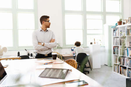 Young businessman standing in officeの写真素材