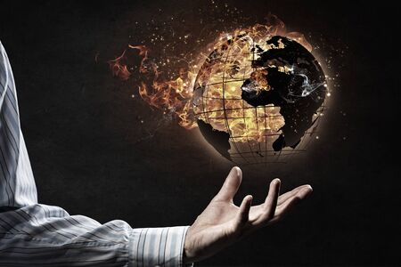 Hand of businessman holding globe in fire flamesの写真素材