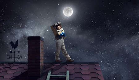 Funny girl in space costume on house roof dreaming she is astronautの写真素材