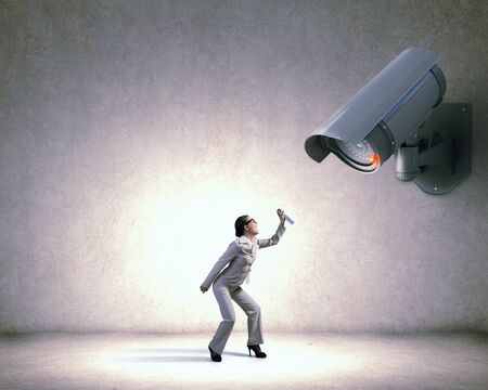 Unrecognizable businesswoman in room standing under security cameraの写真素材