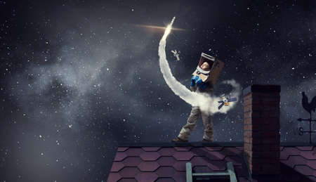 Funny girl in space costume on house roof dreaming she is astronautの写真素材