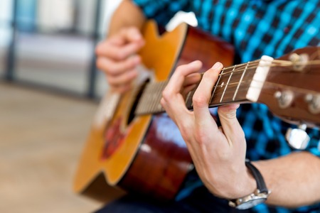 Man in casual clothes playing guitar in office