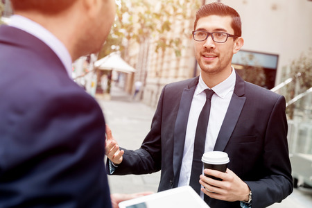 Two businessmen talking outdoors while taking coffee breakの写真素材