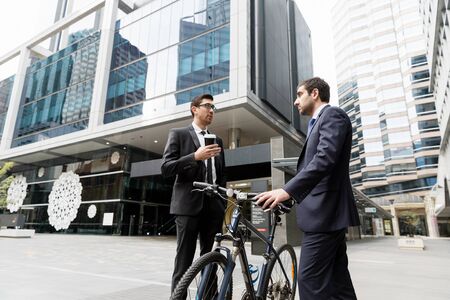 Young businessman with bike talking to his colleagueの写真素材