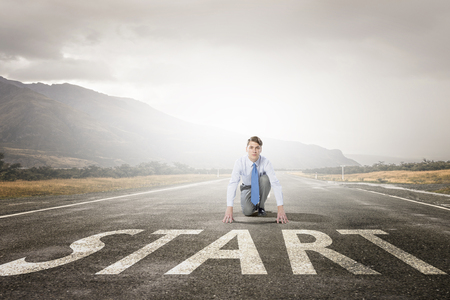 Young businessman in start pose on road ready to runの写真素材