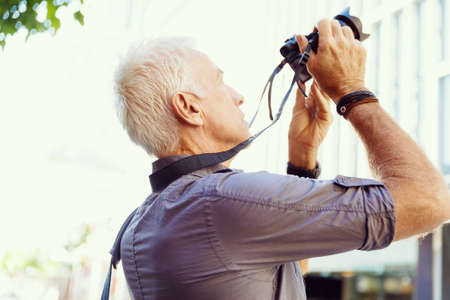 Senior man with camera in cityの写真素材