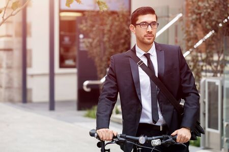 Young businessman wearing suit with bike outdoorsの写真素材