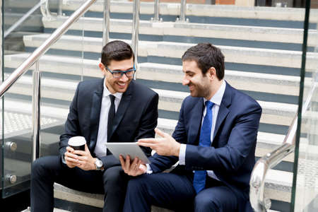 Two businessmen talking outdoors while taking coffee breakの写真素材
