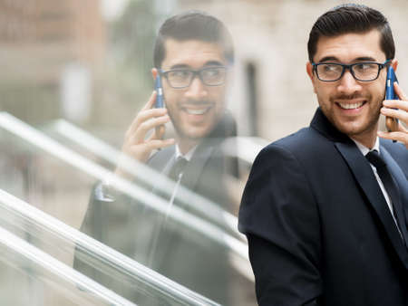 Portrait of young handsome businessman outdoor holding mobile phone