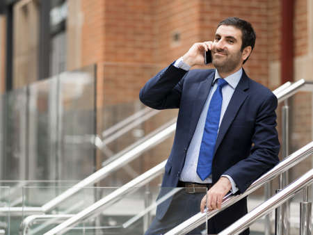 Portrait of young handsome businessman outdoor holding mobile phoneの写真素材