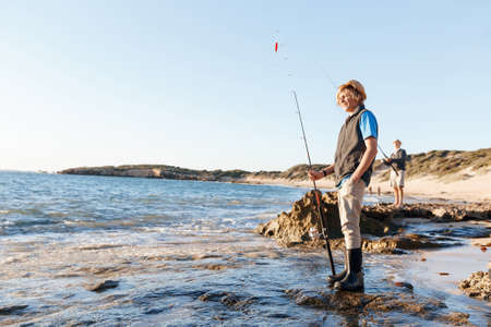 Teenage boy fishing with rod at seaの写真素材