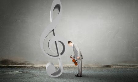 Young violinist in interior leaning head on music noteの写真素材