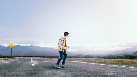 Teenager guy riding skateboard on asphalt roadの写真素材