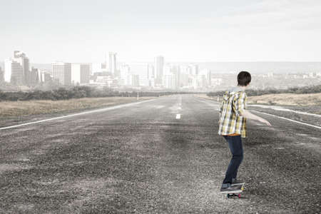 Teenager guy riding skateboard on asphalt roadの写真素材