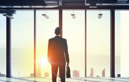 Back view of businessman against panoramic office window. Mixed mediaの写真素材