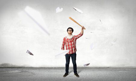 Young hipster guy with bat on asphalt roadの写真素材