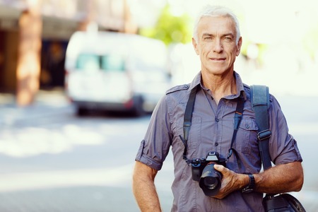 Senior man with camera in cityの写真素材