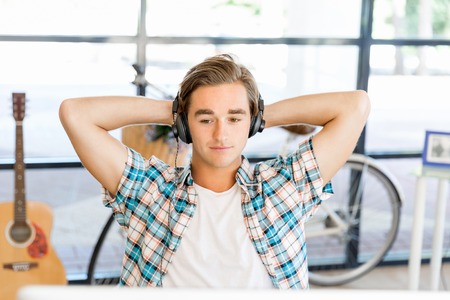 Young man in casual clothes in an office in headphonesの写真素材