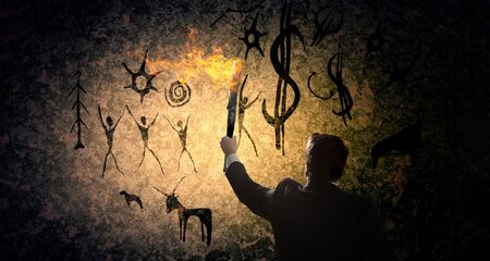 Young businessman in darkness holding burning torch in handの写真素材