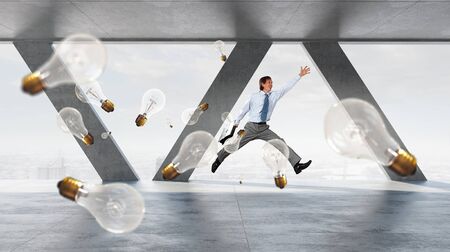 Cheerful businessman in office interior jumping high. Mixed media