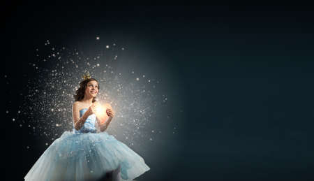 Little cute princess in dress and crown with heart in handsの写真素材