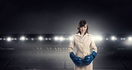 Young businesswoman in blue boxing gloves competition readyの写真素材