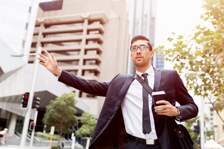 Young businessman wearing suit catching taxiの写真素材