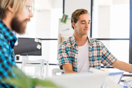 Two young office workers working together at the deskの写真素材
