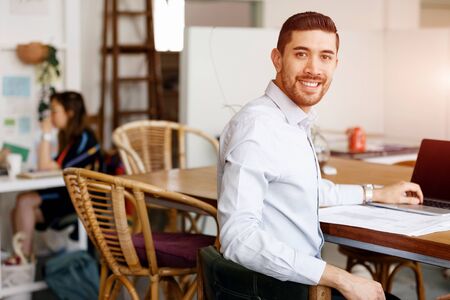 Young businessman sitting at desk and working in officeの写真素材