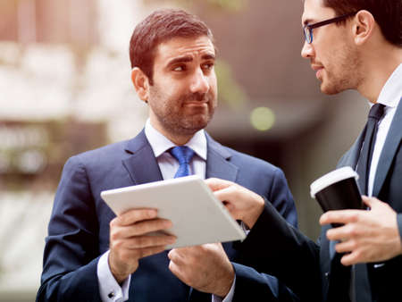 Two businessmen talking outdoors while taking coffee breakの写真素材