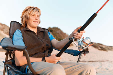 Teenage boy fishing with rod at seaの写真素材