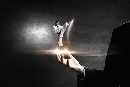 Close of businessman holding in palm karate fighterの写真素材