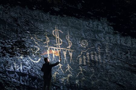 Young businessman in darkness holding burning torch in handの写真素材