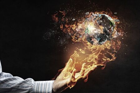 Burning Earth Planet in male palm. Elements of this image are furnished by NASA