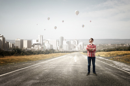 Young hipster guy in glasses and checked shirt on asphalt roadの写真素材