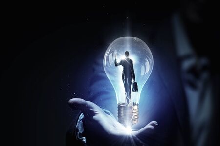 Close view of businesswoman holding in palm glass light bulbの写真素材