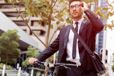 Young businessman wearing suit with bike outdoorsの写真素材