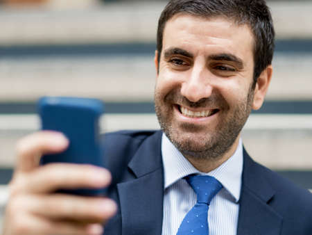 Portrait of young handsome businessman outdoor holding mobile phoneの写真素材