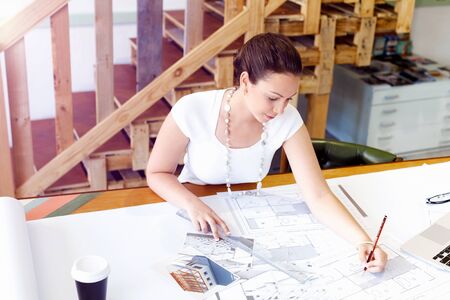 Young woman in casual clothes in an office with draftsの写真素材