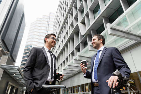 Two businessmen talking outdoors while taking coffee breakの写真素材