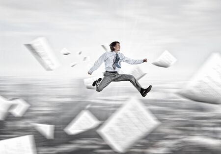 Young cheerful businessman jumping high presenting success conceptの写真素材