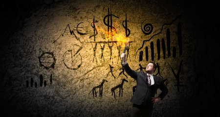Young businessman in darkness holding burning torch in handの写真素材