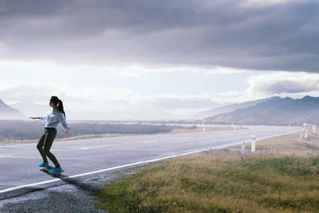 Teenager active girl riding skateboard on asphalt roadの写真素材
