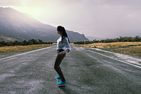Teenager active girl riding skateboard on asphalt roadの写真素材