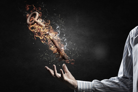 Key as security or success symbol burning in fire on palmの写真素材