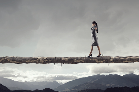 Blind businesswoman walking on wooden log above gap. Risk and challenge concept . Mixed mediaの写真素材