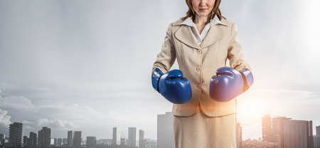 Businesswoman in boxing gloves against city background . Mixed mediaの写真素材