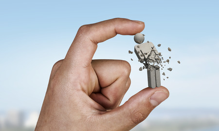 Close of male hand holding stone figure between fingers . Mixed mediaの写真素材