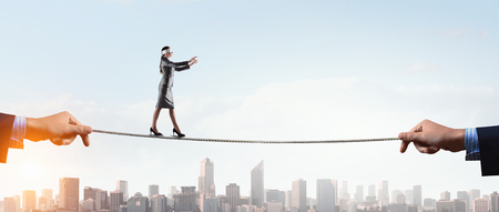 Businesswoman with blindfolder on eyes balancing on the rope . Mixed mediaの写真素材