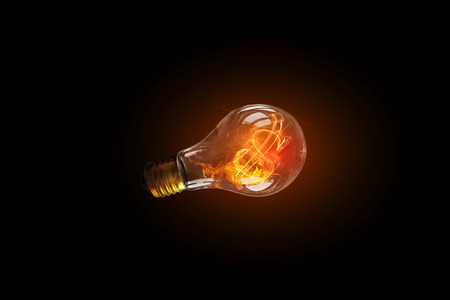 Glass glowing light bulb on dark background . Mixed media